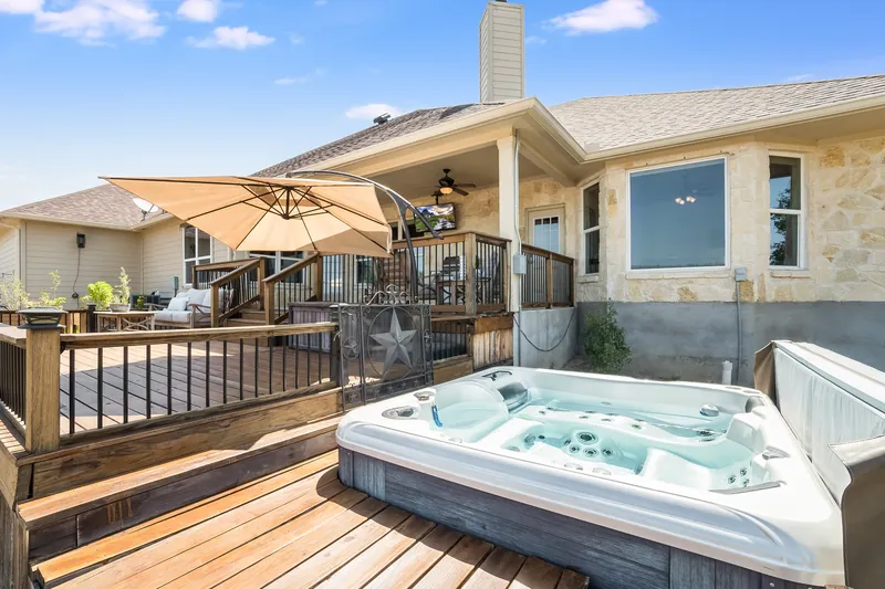 Hot tub set into a residential backyard deck beside a home.