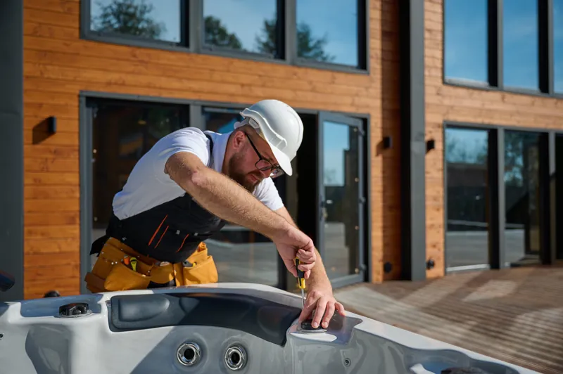 Hot tub repair technician adjusting an outdoor spa’s topside control panel in Palm Beach County.