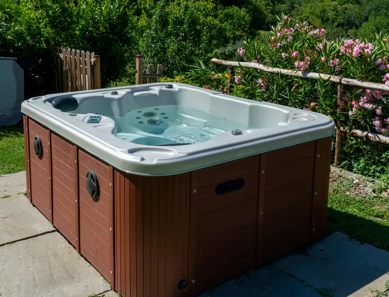Residential hot tub with a wood-look cabinet on a garden patio.